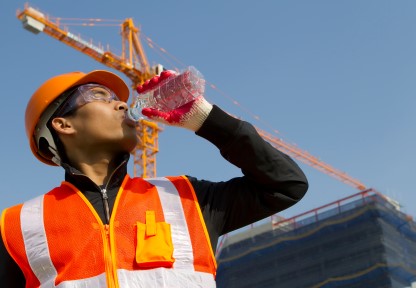  worker man  as he drinks from a plastic water bottle on construction site